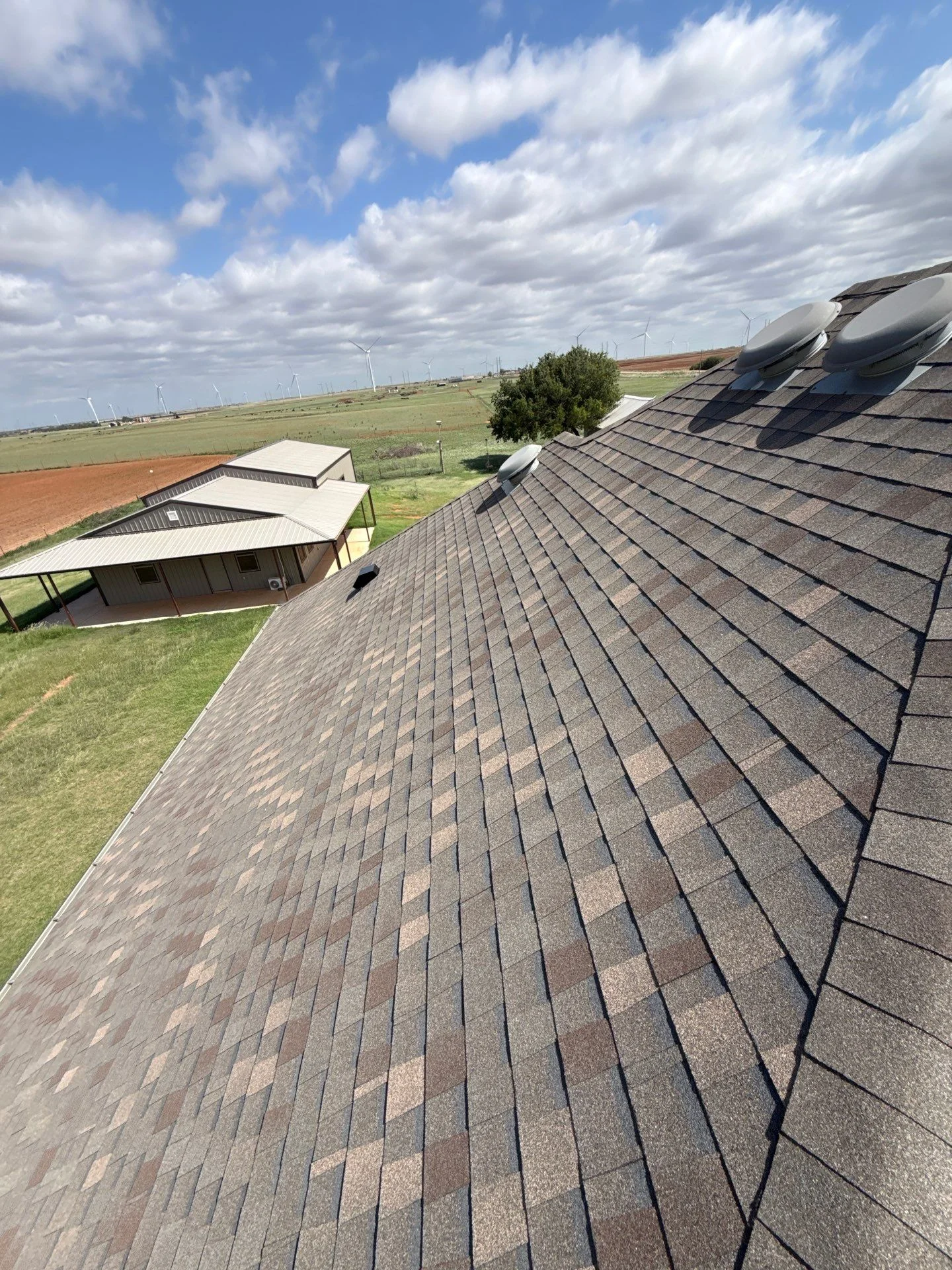 Charcoal architectural shingles installed on multi-plane residential roof with proper alignment and ridge caps