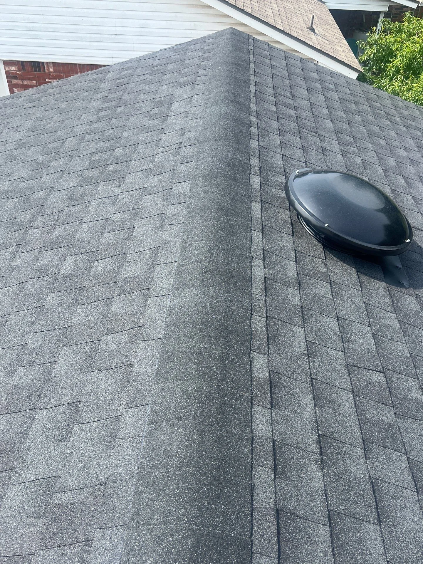 Charcoal gray architectural shingles with black roof vent installed on residential roof