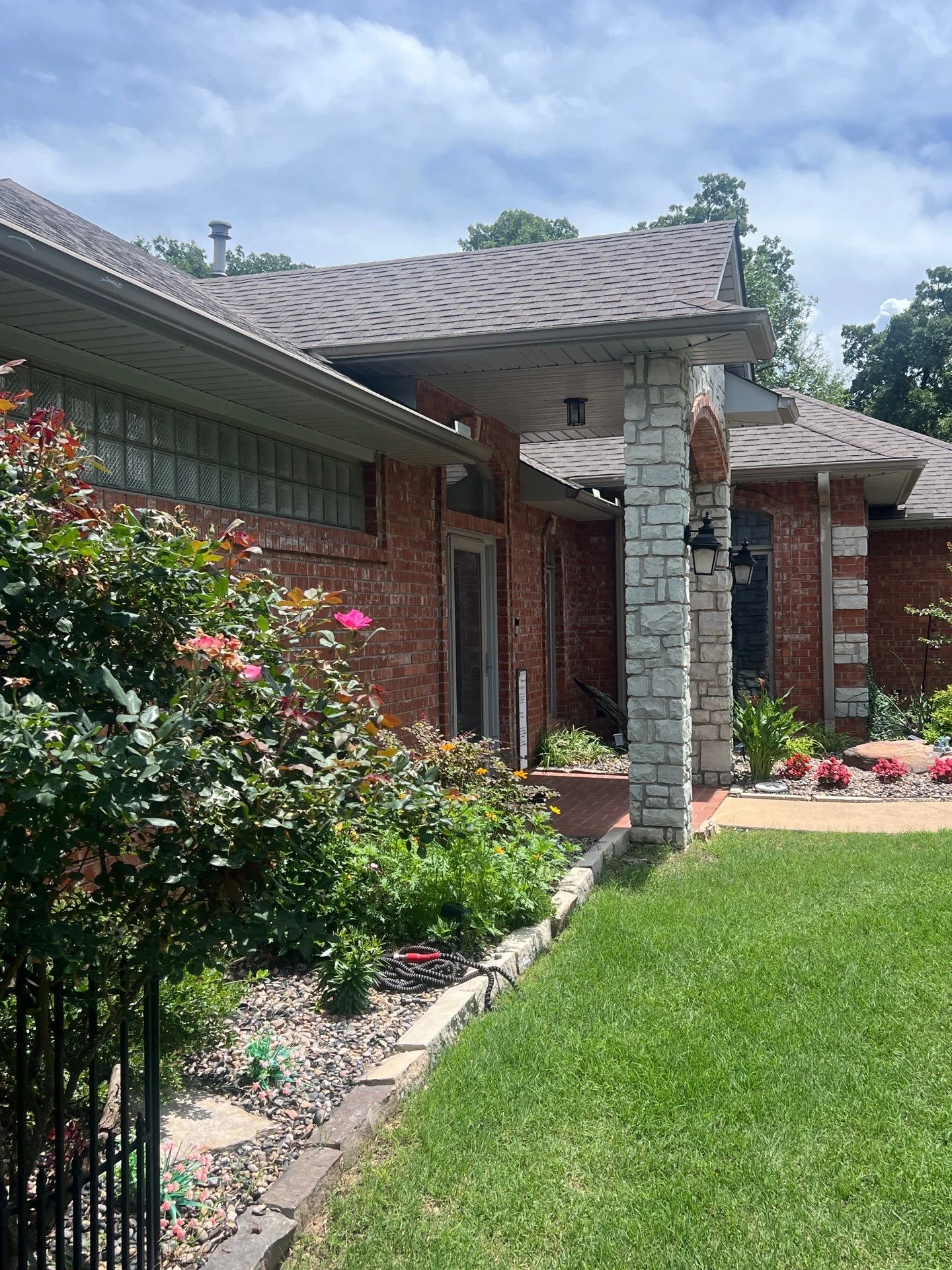 New gray architectural shingles installed on brick home with stone entry column