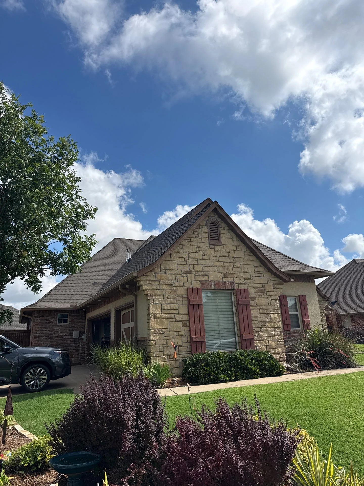Brick home with new charcoal gray dimensional asphalt shingle roof and gable vents