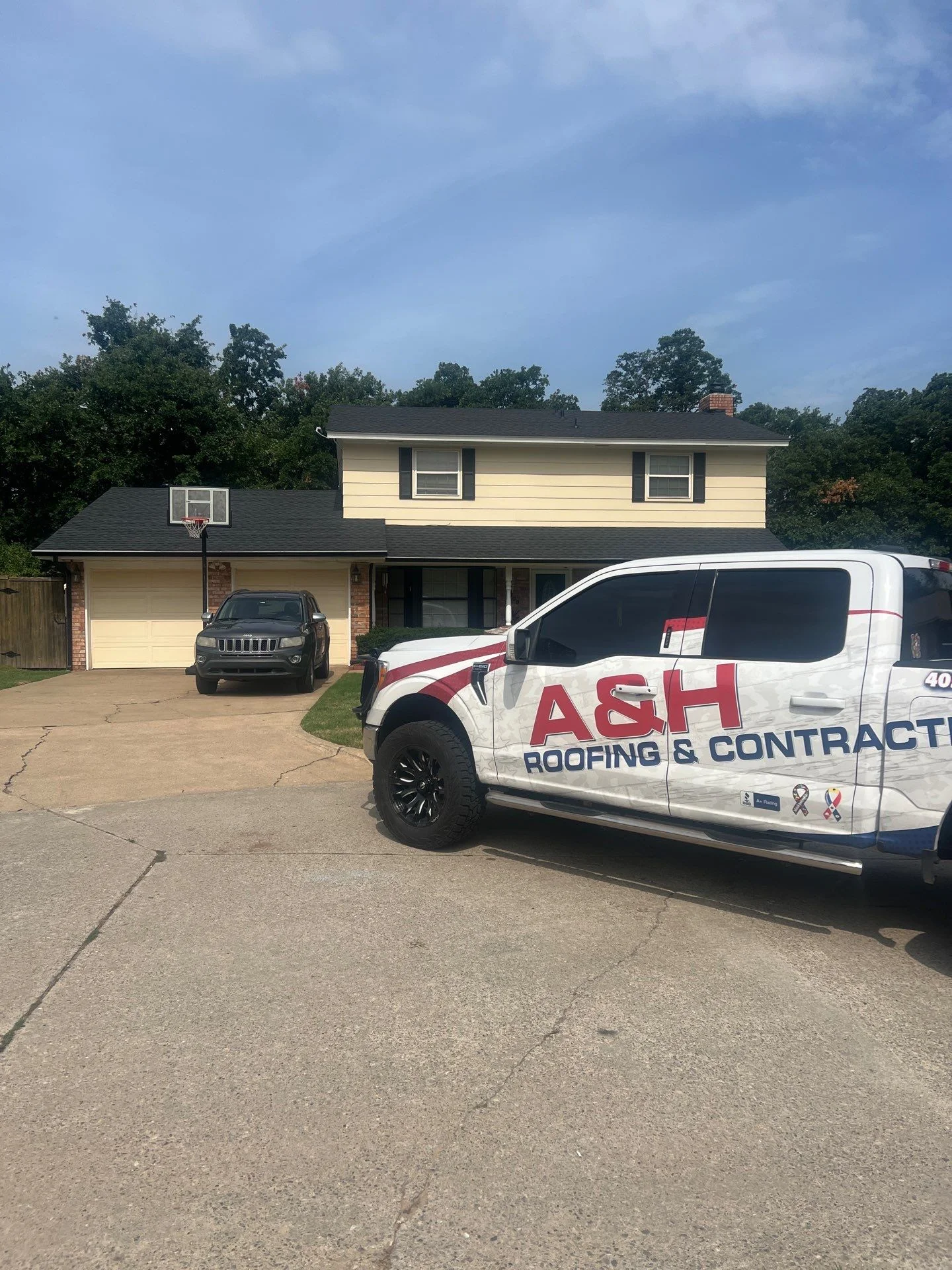 Two-story home with new dark gray asphalt shingle roof installation on main house and garage
