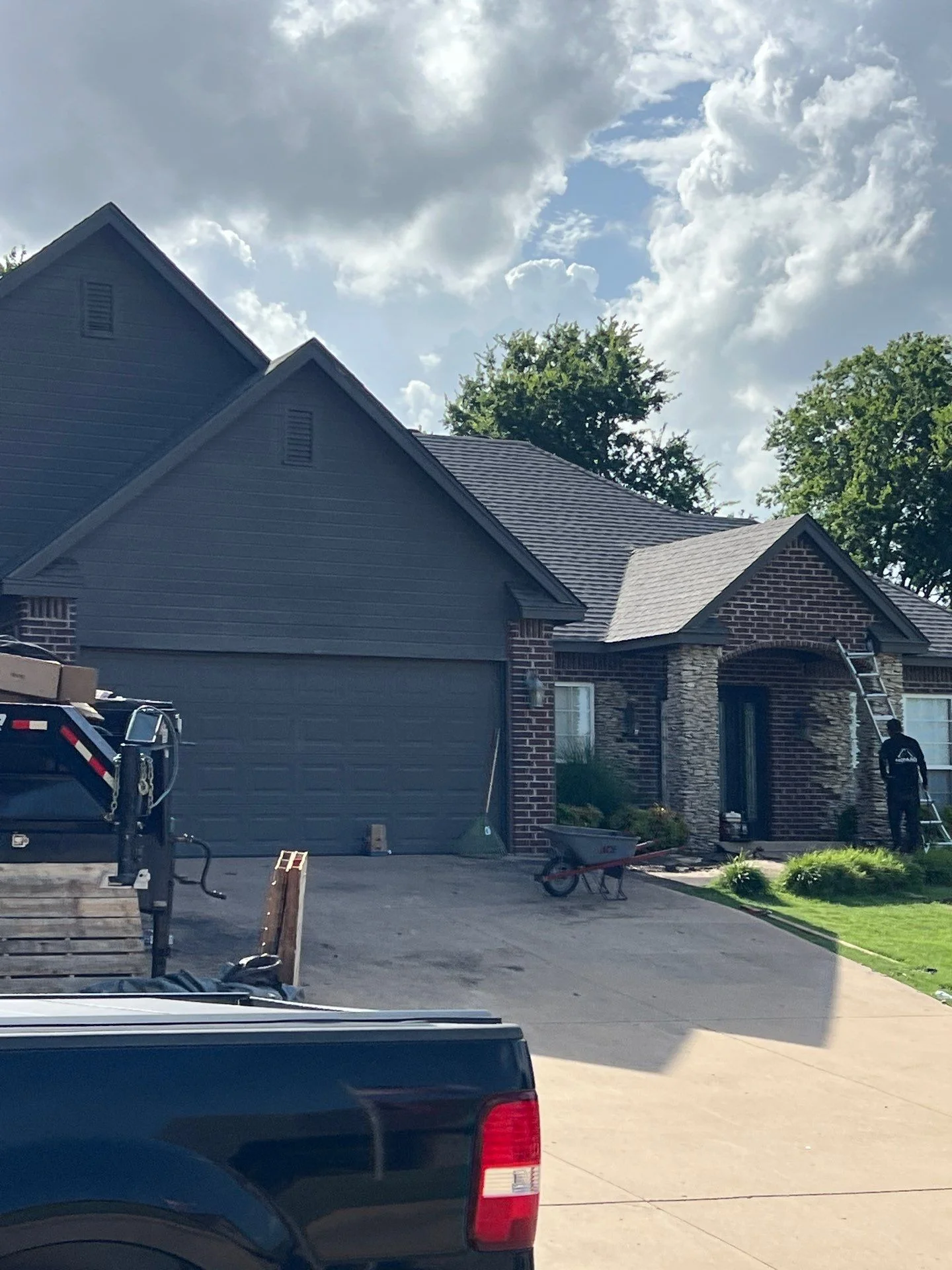 New gray architectural shingles installed on multi-plane residential roof with brick home exterior