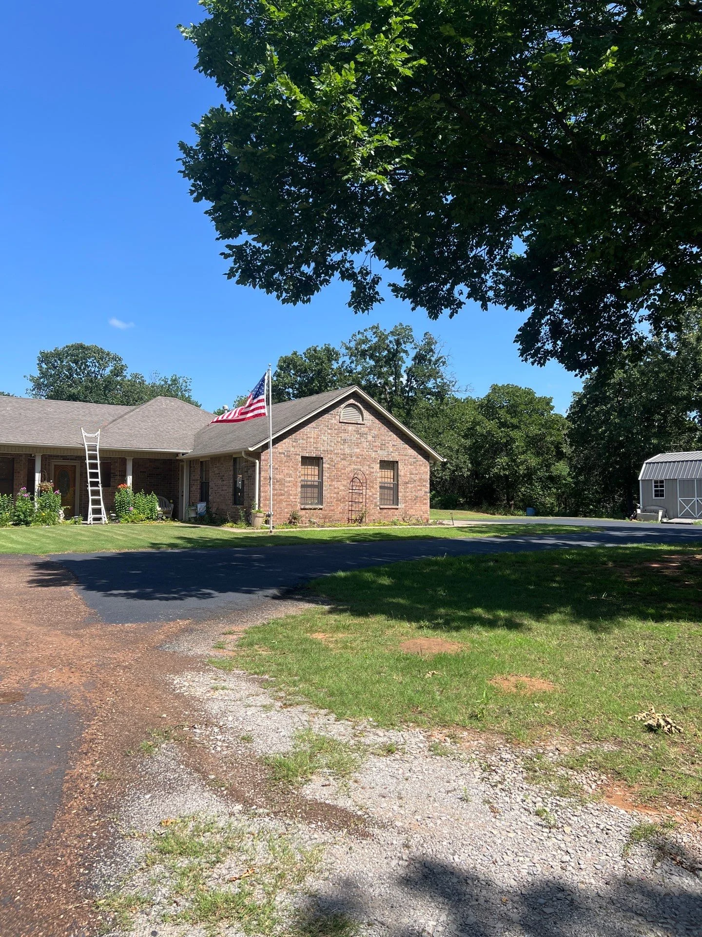 Gray architectural shingle roof on brick home with covered porch and driveway