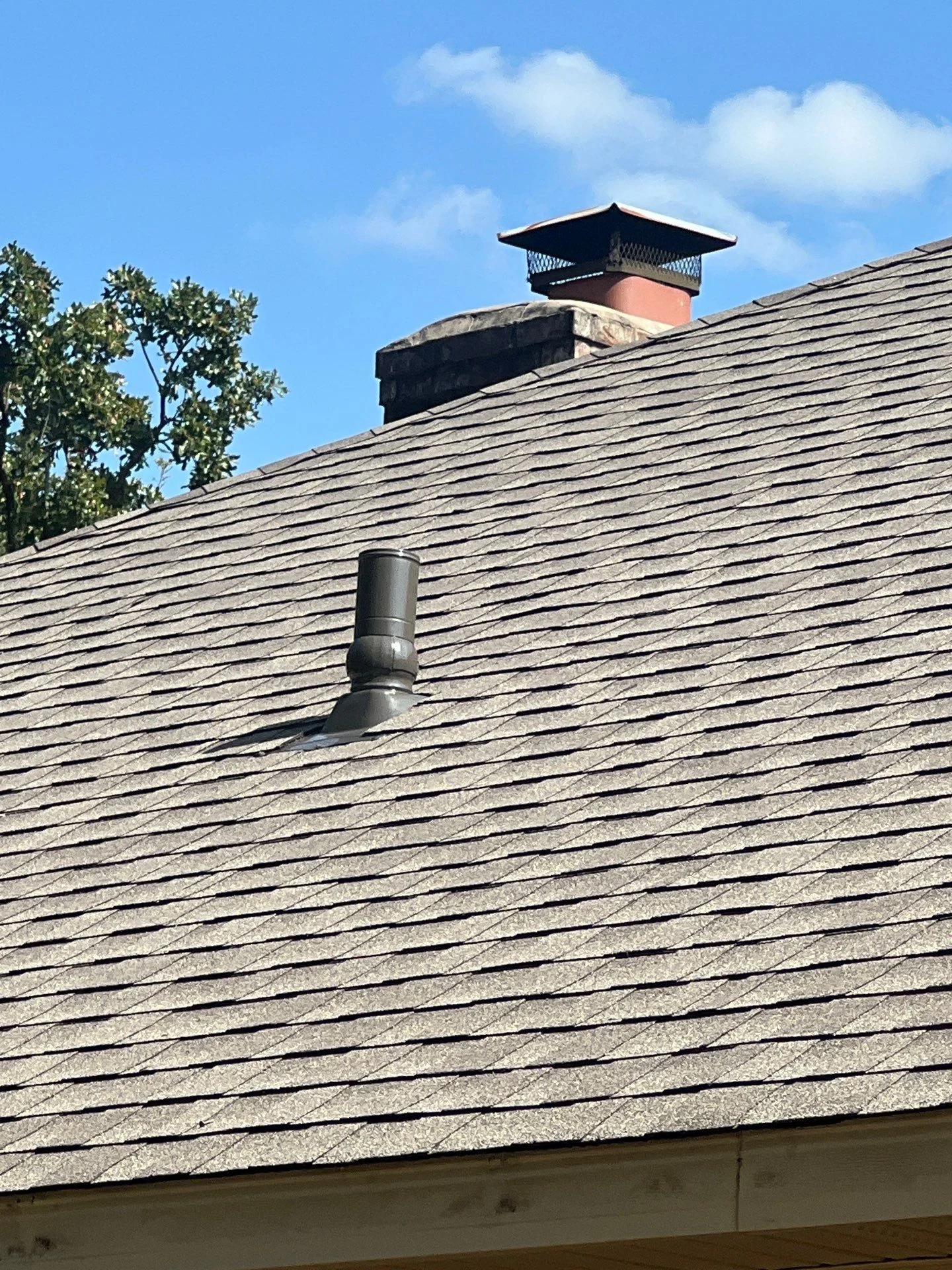 Asphalt shingle roof with terra cotta chimney, metal vent pipe, and black flashing