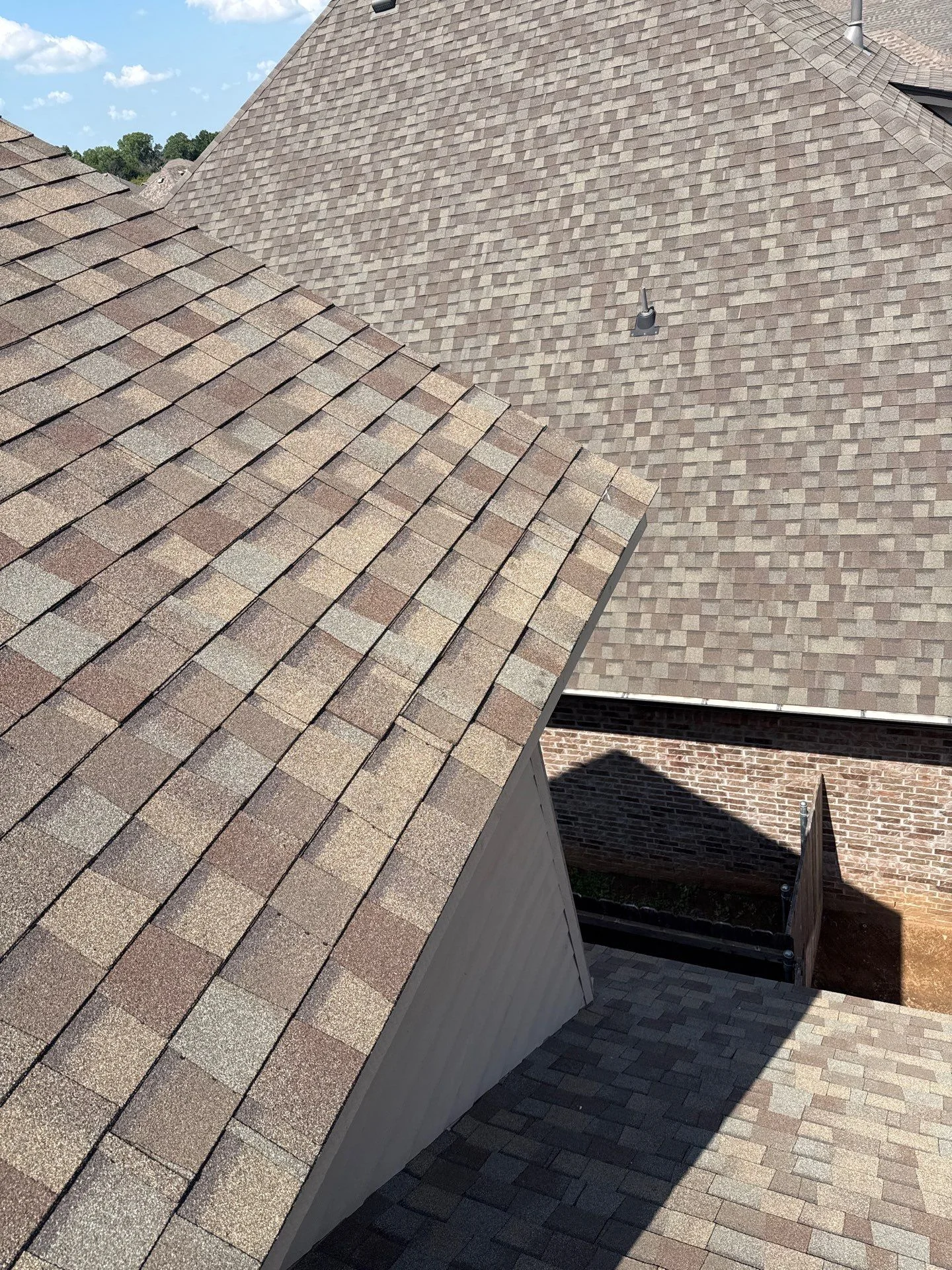 Newly installed architectural shingles on pitched roof with multiple angles and dormers