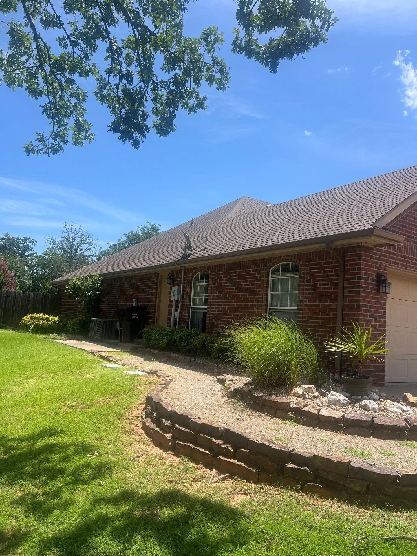 Gray asphalt shingle roof on brick home with new gutters and fascia