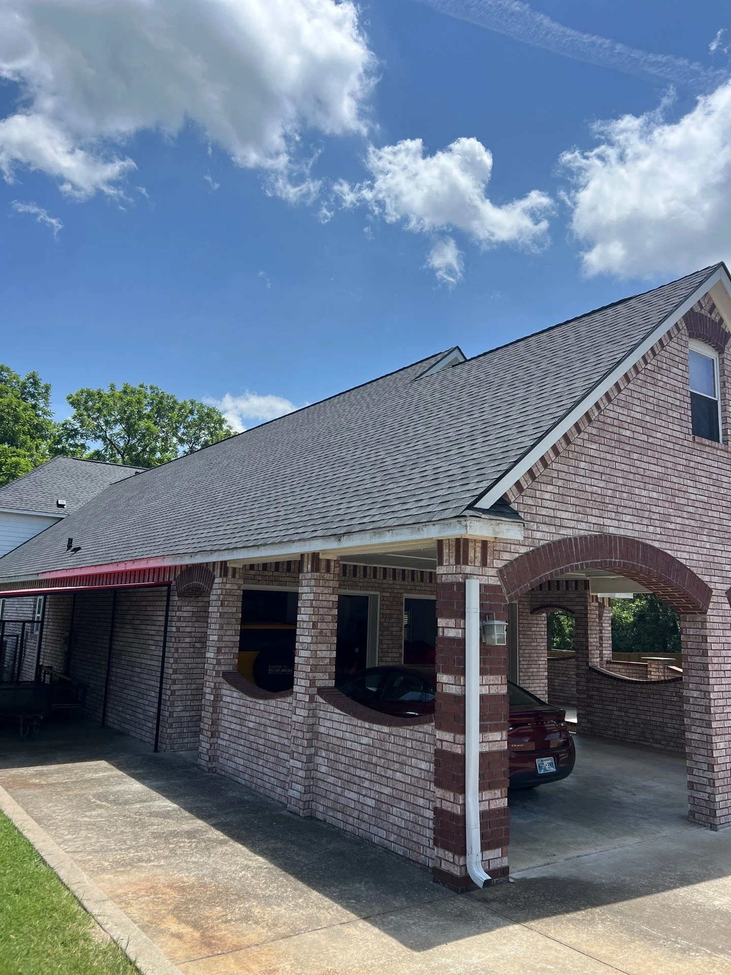 New gray architectural shingle roof on brick home with covered carport and white trim