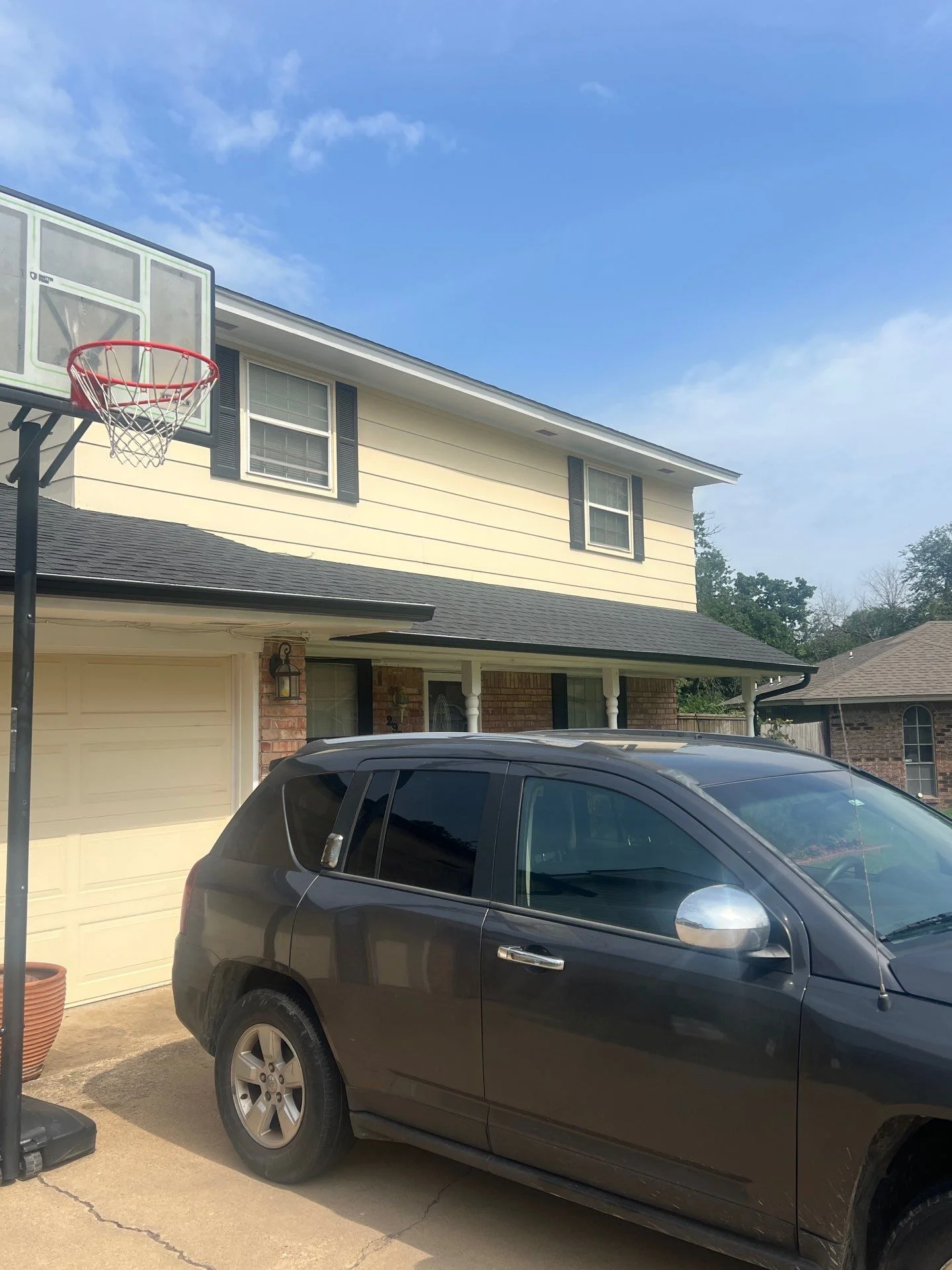 Two-story home with new charcoal gray asphalt shingle roof and covered porch