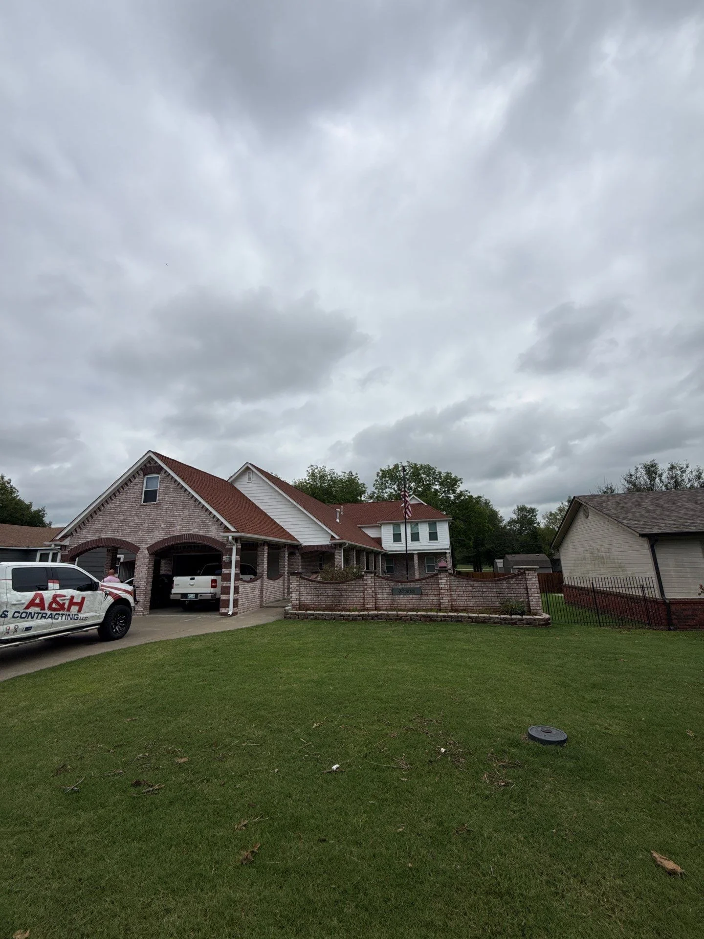 Two-story brick home with new burgundy asphalt shingle roof installation