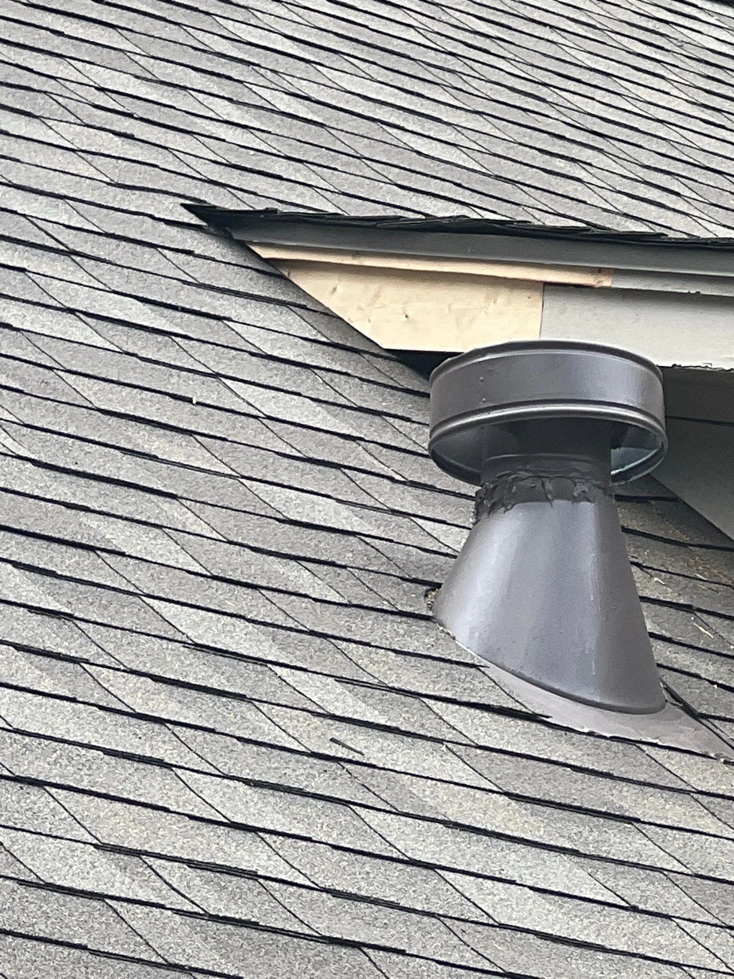 Gray metal roof vent with flashing installed on gray asphalt shingle roof