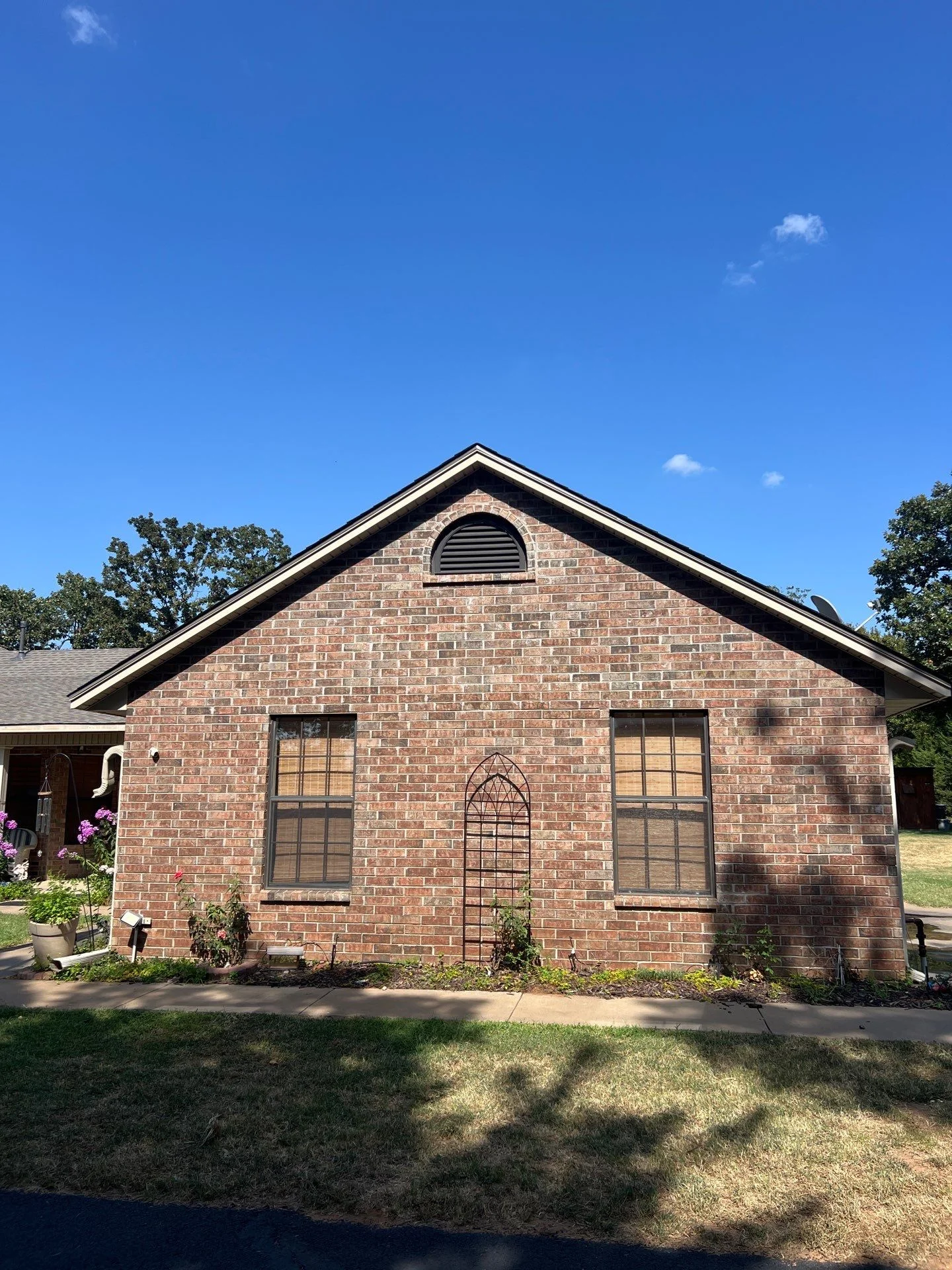 Brick gable roof with new asphalt shingles, black trim, and gable vent installation